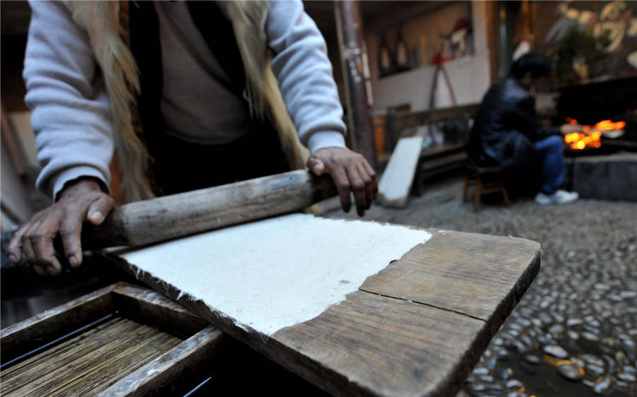 Le procédé de calandrage lors de la fabrication du papier Dongba. [Photo / Xinhua ]