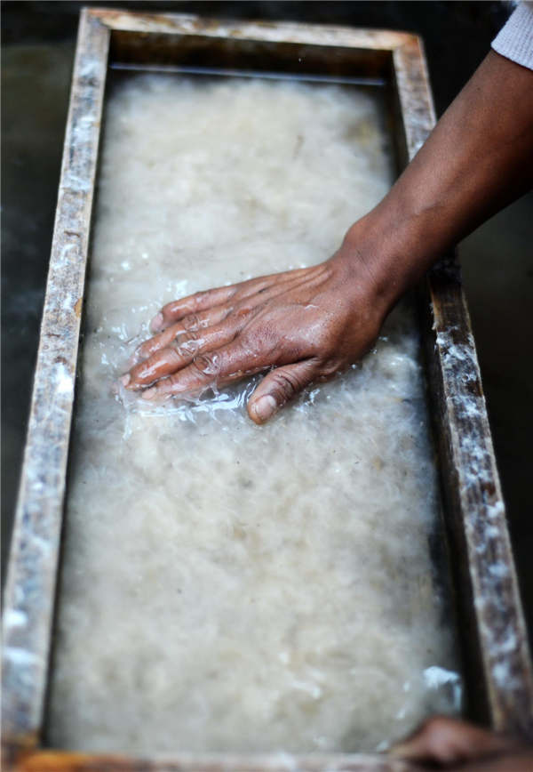 Le processus du battage lors de la fabrication du papier Dongba. [Photo / Xinhua ]