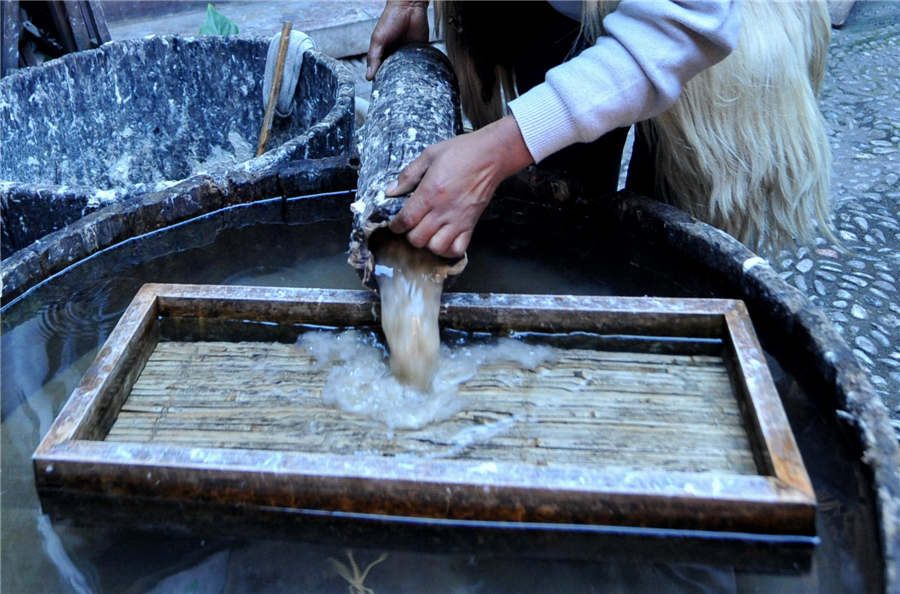 He Liwei déverse la mixture dans un moule en bois. [Photo / Xinhua ]