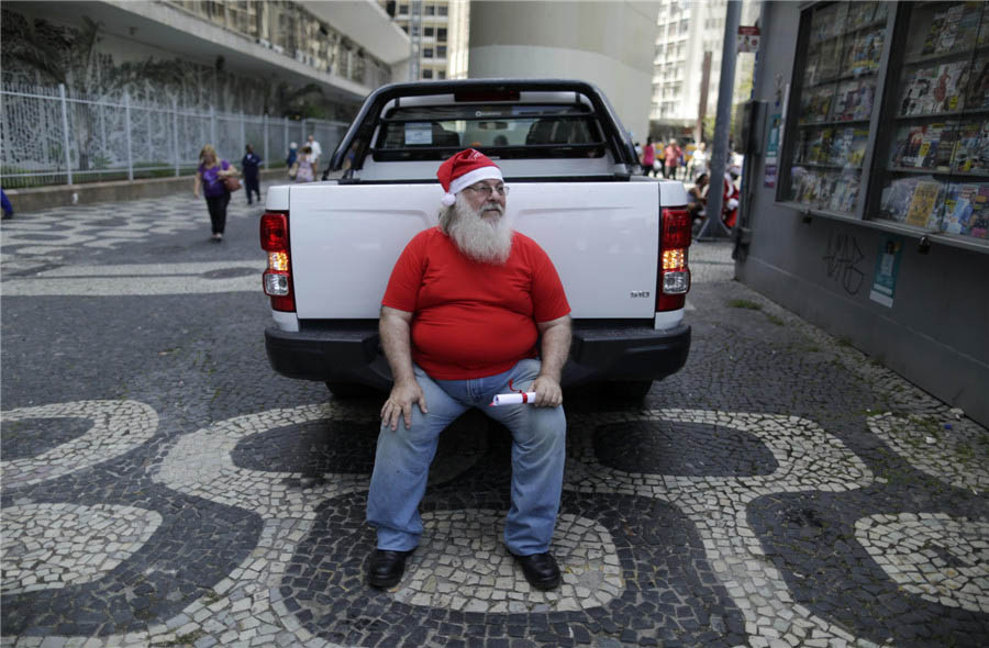 Un étudiant de l'école brésilienne des Pères Noël tient son diplôme alors qu'il se repose après la cérémonie de remise des diplômes à Rio de Janeiro, le 12 novembre 2013. [Photo / agences]