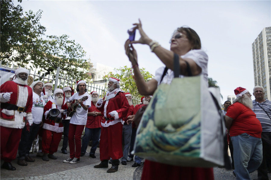 Une femme prend des photos d'hommes habillés en Père Noël, lors de la cérémonie de remise des diplômes de l'école brésilienne des Pères Noël à Rio de Janeiro, le 12 novembre 2013. [Photo / agences]