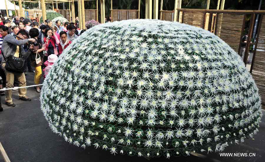 Des visiteurs regardent une sculpture composée de 1 688 fleurs de chrysanthème lors d'une exposition sur les  chrysanthèmes, à Taiwan au Sud-est de la Chine, le 17 novembre 2013. L'exposition s'est ouverte dimanche et durera jusqu'au 1er décembre. [Photo / Xinhua]