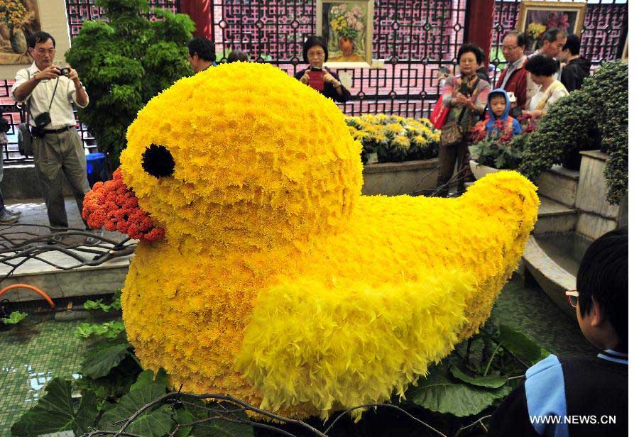 Des visiteurs regardent un « canard jaune » composé de 2 400 fleurs de chrysanthème lors d'une exposition sur les  chrysanthèmes à Taiwan au Sud-est de la Chine, le 17 novembre 2013. L'exposition s'est ouverte dimanche et durera jusqu'au 1er décembre. [Photo / Xinhua]