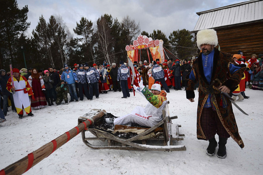 Le relayeur de la flamme olympique des Jeux d'hiver de Sotchi, Alexander Chudnovskiy, monte sur un traîneau du musée Taltsy dans la région d'Irkoutsk, document du Comité d'organisation de Sotchi 2014 publié le 23 novembre 2013.