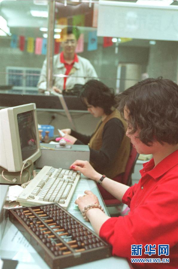 Une photo prise en 1996, qui montre une employée d'une banque travaille avec un ordinateur et un boulier chinois. (Photo : Xinhua/Zhang Yaozhi)