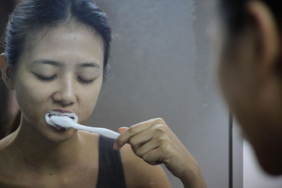 Lei Xiaomi, un modèle à temps partiel pour les vendeurs en ligne, se brosse les dents, il est 6 heures, nous sommes à Guangzhou, la province de Guangdong (sud de la Chine), le 28 novembre 2013. La jeune femme est diplômée en fashion design à l'Académie des Beaux-Arts de Guangzhou. Elle passe plus de la moitié de la semaine à faire du mannequinat pour Taobao, la célèbre plate-forme chinoise de vente en ligne. Lei a confié aimer ce travail et son salaire servira à réduire la charge de ses parents.