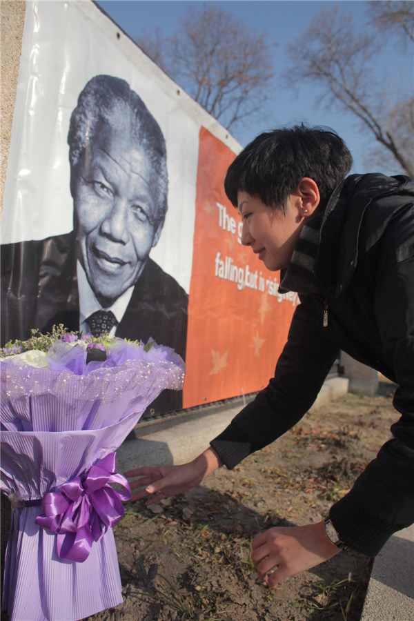 Une femme dépose des fleurs en face de l'ambassade d'Afrique du Sud à Beijing le 6 décembre 2013 en hommage à l'ancien président sud-africain Nelson Mandela. [Photo Wang Jing / Asianewsphoto]