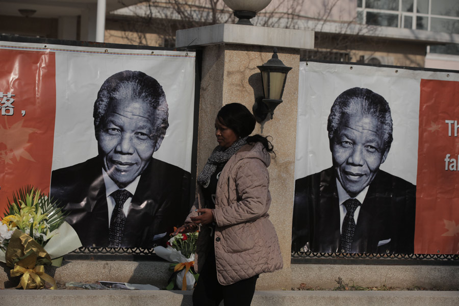 Une femme rend hommage à Nelson Mandela en face de l'ambassade d'Afrique du Sud à Beijing, le 6 décembre 2013. [Photo Wang Jing / Asianewsphoto]