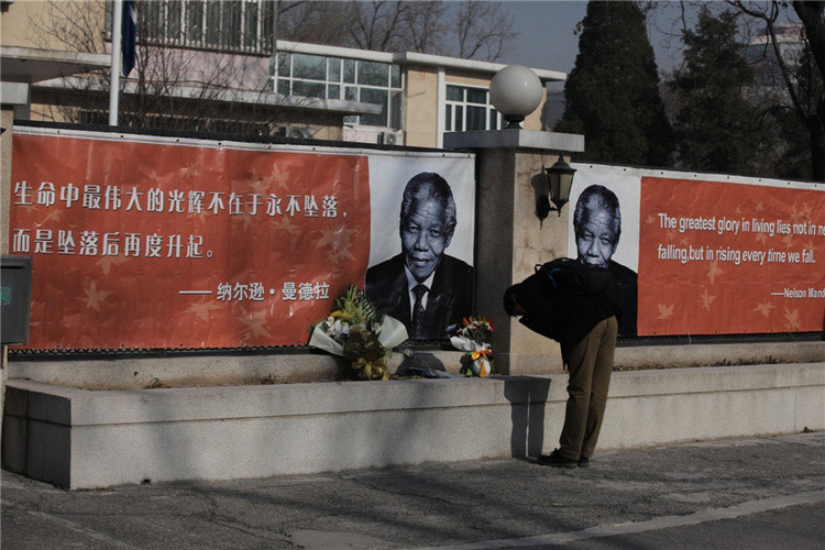 Un homme rend hommage à Nelson Mandela en face de l'ambassade d'Afrique du Sud à Beijing, le 6 décembre 2013. [Photo Wang Jing / Asianewsphoto]