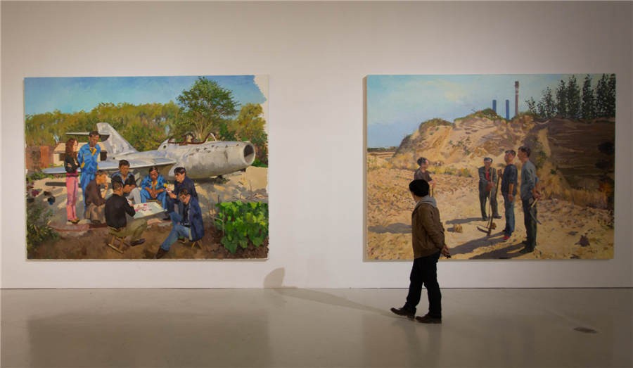 Un visiteur regarde quelques peintures à l'exposition d'art présentant des oeuvres des enseignants de l'ACBC à l'Académie Centrale des Beaux-Arts de Chine. [Photo fournie au China Daily]