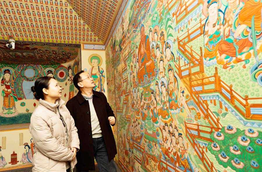 Yang Dongmiao (à gauche) et son mari Jin Weidong regardent la fresque restaurée et terminée de la grotte n° 45 de Mogao à Xi'an, capitale de la Province du Shaanxi, dans le Nord-ouest de la Chine, le 10 décembre 2013. [Photo / Xinhua]