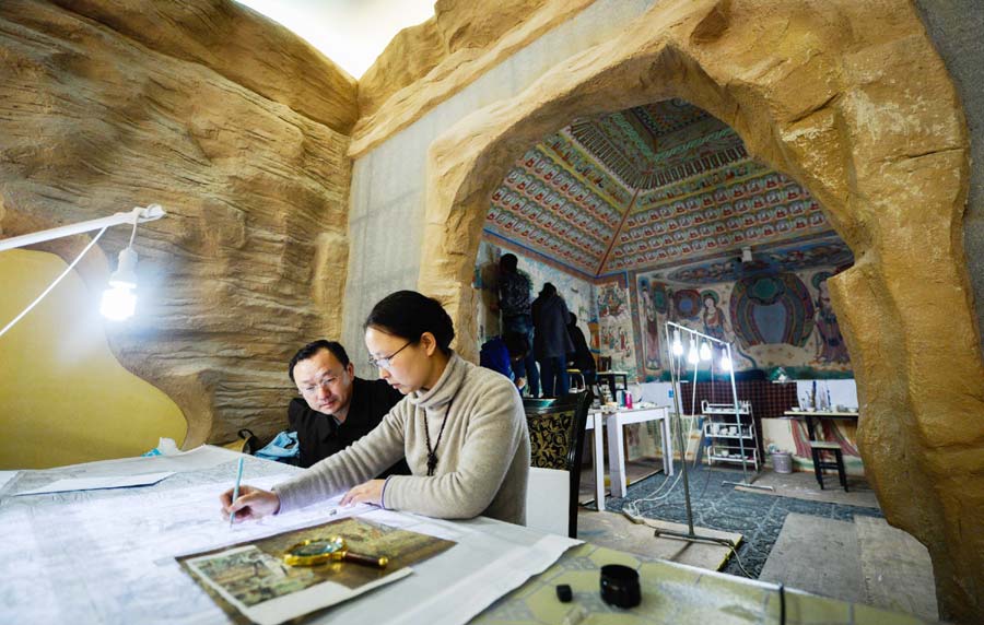 Yang Dongmiao (à gauche) et son mari Jin Weidong regardent la fresque restaurée et terminée de la grotte n° 45 de Mogao à Xi'an, capitale de la Province du Shaanxi, dans le Nord-ouest de la Chine, le 10 décembre 2013. [Photo / Xinhua]