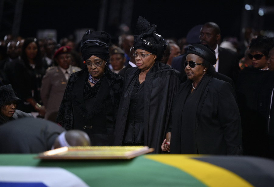 L'ex- épouse de l'ancien président sud-africain Nelson Mandela, Winnie Mandela (à gauche), et la veuve de Mandela, Graça Machel (au centre), devant le cercueil de Mandela lors de ses funérailles à Qunu, le 15 décembre 2013. 