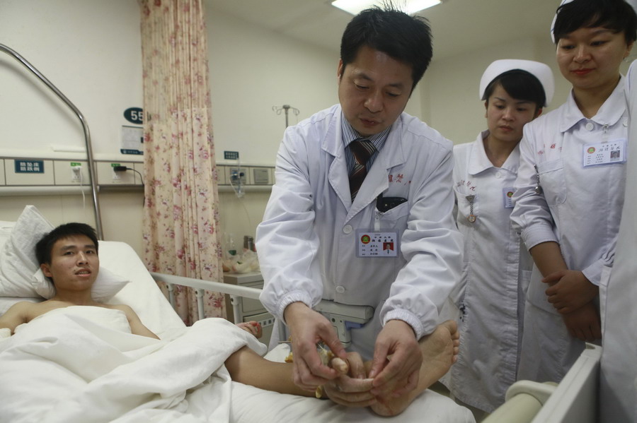 Les médecins vérifient la main droite amputée de Xiao Wei greffée temporairement à sa cheville avant de subir une opération à l'hôpital Xiangya à Changsha, la province du Hunan, le 4 décembre 2013 (document fourni par l'hôpital Xiangya, Central South University). [Photo/agences]