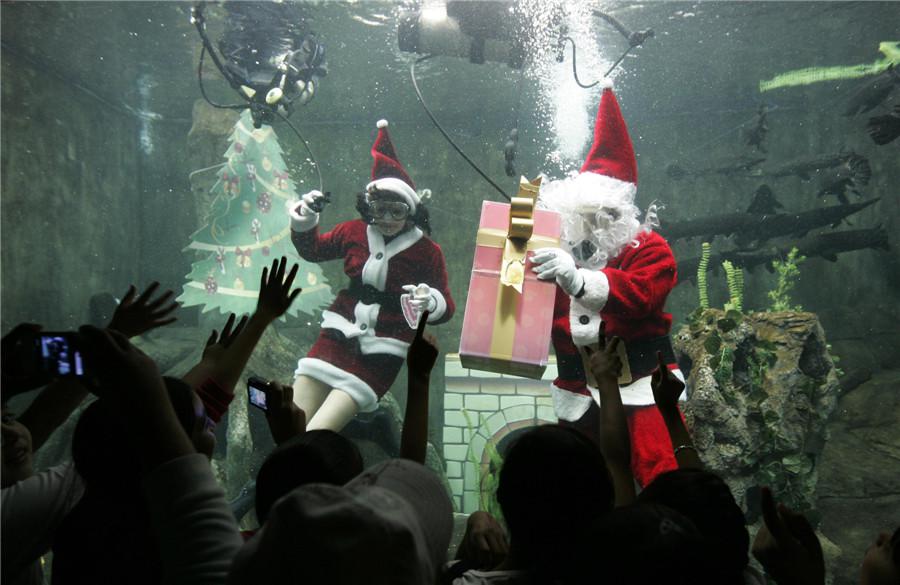 Des plongeurs habillés en Monsieur et Mme Noël nagent dans un aquarium en accueillant des enfants à l'aquarium Guadalajara à Zapopan, le 20 décembre 2013. [Photo / agences]