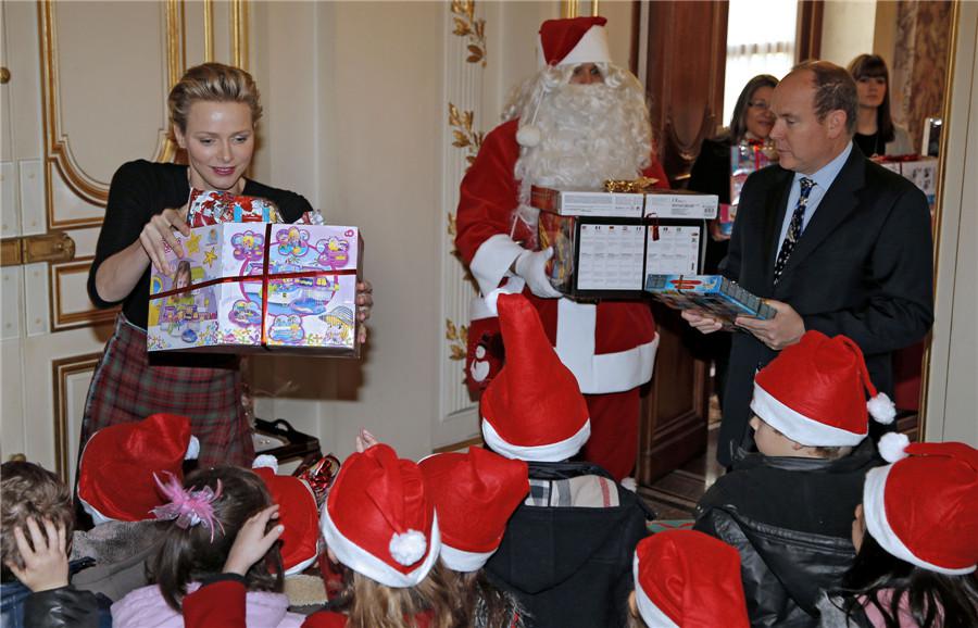 Le Prince Albert II de Monaco (à droite) et son épouse la princesse Charlene (à gauche) distribuent des cadeaux aux enfants de Monaco à côté d'un Père Noël lors de la cérémonie traditionnelle de l'arbre de Noël au Palais de Monaco, dans le cadre de la saison des vacances de Noël à Monaco, le 18 décembre 2013. [Photo / agences]