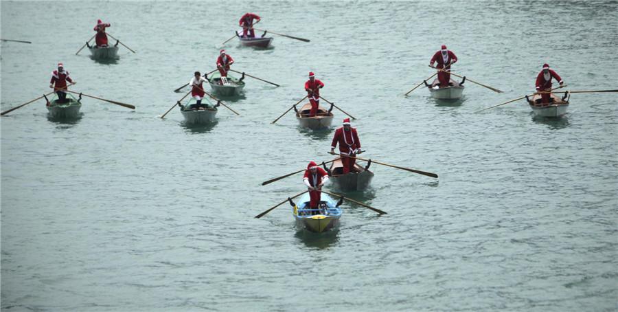 Des gens vêtus de costumes de Père Noël font du bateau sur le Grand Canal de Venise, le 21 décembre 2013. [Photo / agences]