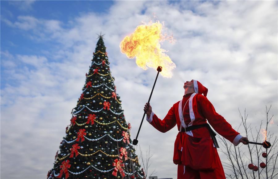 Un fêtard vêtu d'un costume de Père Noël crache du feu lors d'un défilé dans la ville de Krasnodar, dans le sud de la Russie, le 21 décembre 2013. [Photo / agences]