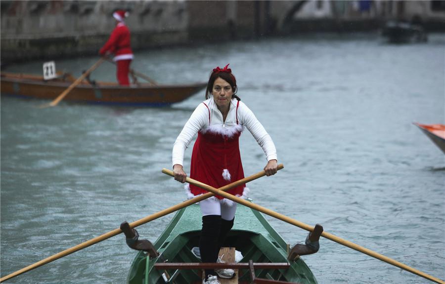 Une femme vêtue d'un costume de Père Noël dirige un bateau sur le Grand Canal de Venise, le 21 décembre 2013. [Photo / agences]