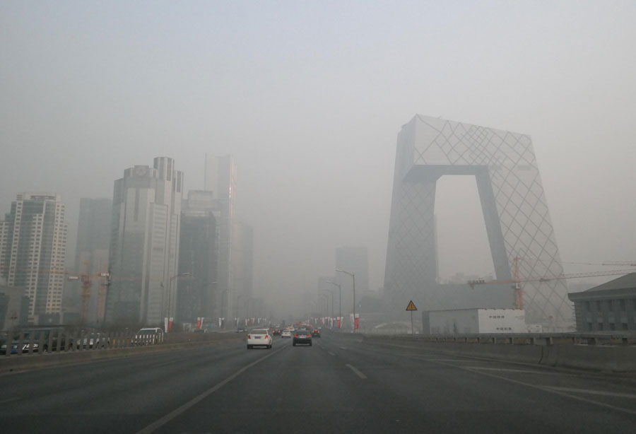 Des véhicules se déplacent sur une route pendant une période de fort smog à Beijing, le 24 décembre 2013. [Photo / Xinhua]