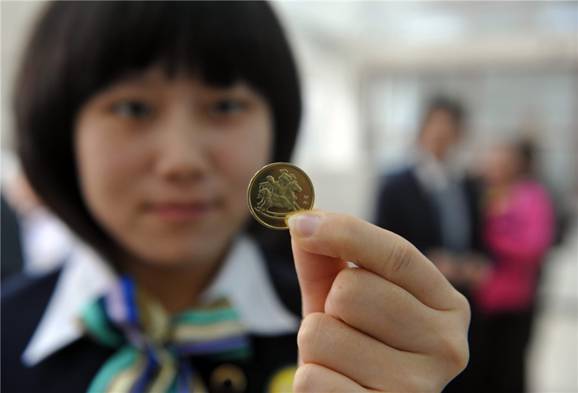 Une femme montre une pièce d'1 Yuan (0,16 Dollar US) commémorant l'Année lunaire chinoise du Cheval à Qionghai, dans la Province de Hainan, le 24 décembre 2013.
