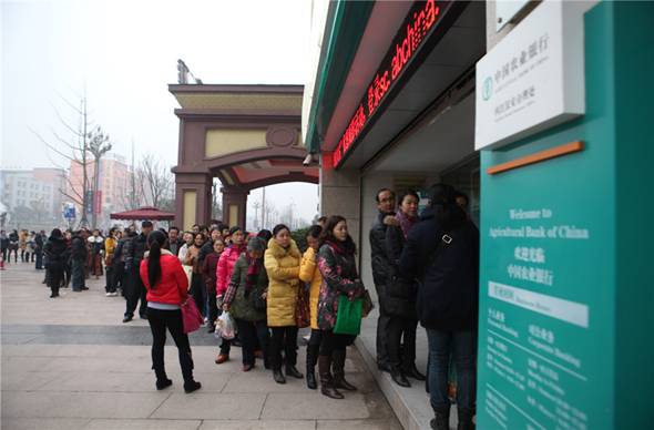 Des gens attendent à l'extérieur d'une banque pour acheter des pièces commémoratives pour l'Année lunaire chinoise du Cheval, le 24 décembre 2013 à Shanghai.