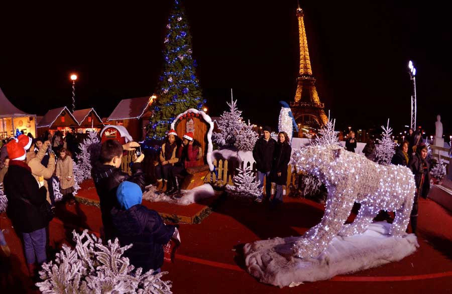 Le 23 décembre, quelque touristes prennent des photos avec les décorations de Noël près de la Tour Eiffel.