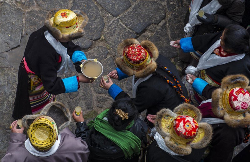 Des femmes tibétaines trinquent avec du vin d'orge de montagne au monastère de Jokhang, l'un des principaux monastères du Tibet pendant le festival de la Déesse de bon augure, le 13 décembre 2013. [Photo Xinhua]