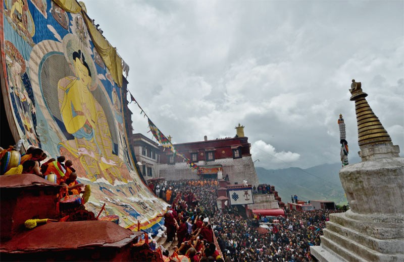 Des lamas déroulent une immense peinture Thangka lors d'une cérémonie qui se déroule pendant le Festival Shoton au monastère bouddhiste de Gandan, le 22 juillet 2013. Le monastère de Gandan est l'un des six grands monastères de la Secte Gelugpa de la Région Autonome du Tibet. [Photo / Xinhua]