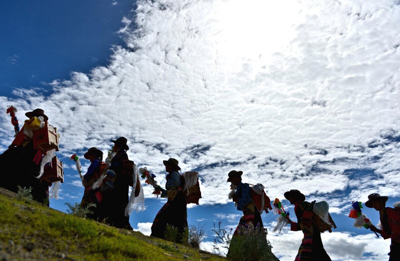 Des Tibétains revêtus de leurs plus beaux atours portent des livres pour préparer le Festival Ongkor, une fête traditionnelle tibétaine, organisée à Lhassa le 10 juillet 2013. [Photo / Xinhua]