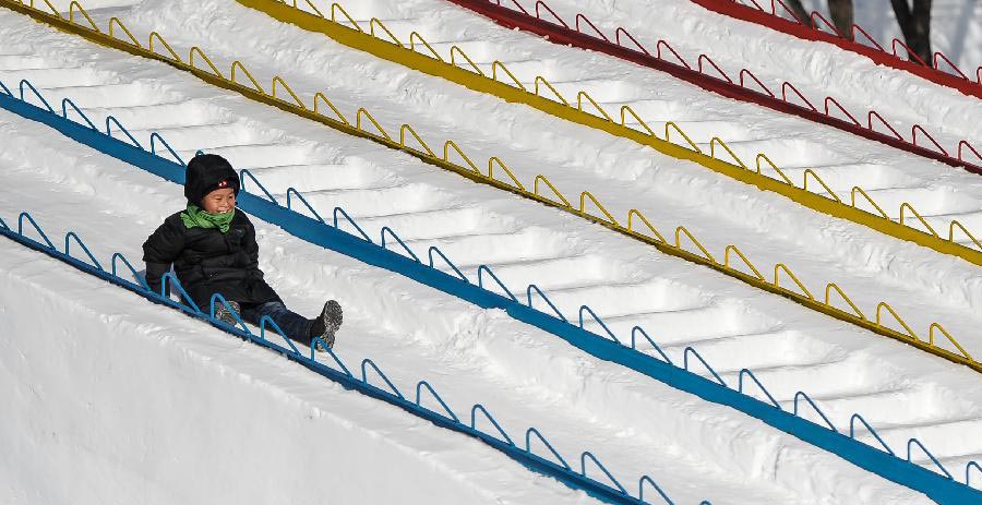 Un enfant joue sur un toboggan de neige dans le parc national forestier Jingyuetan à Changchun, capitale de la province du Jilin, en Chine du Nord, le 2 janvier 2014. Le « Jingyue Snow World », qui compte de nombreuses de sculptures de neige, a été ouvert aux touristes jeudi. [Photo / Xinhua]