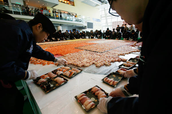 Des sushis vont être distribués gratuitement au public, après ce nouveau record du monde, en créant la plus grande mosaïque de sushis, ce à l'occasion du 10e anniversaire d'une chaîne de magasins de sushi à Hong Kong, le 8 Janvier 2014. [Photo/agences]