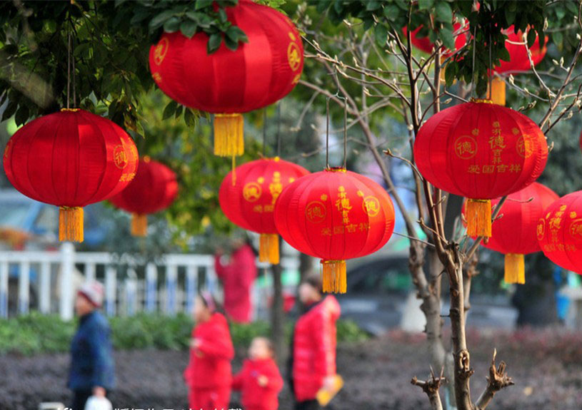 Des habitants passent devant des lanternes rouges attachées sur un arbre dans la ville de Yichang, dans la Province du Hubei, en Chine centrale, le 18 janvier 2014. [photo / icpress.cn]