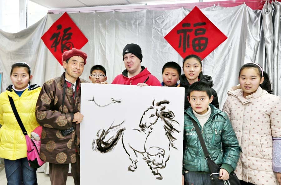 Jonathan, un Américain, a rencontré des artistes folkloristes et des enfants de la communauté de Haocheng pour exécuter une peinture sur le thème du cheval et certains travaux de calligraphie pour accueillir le prochain Nouvel An lunaire -l'Année du Cheval- à Nantong, dans la Province du Jiangsu, le 24 janvier. [Photo Xu Peiqin / Asianewsphoto]