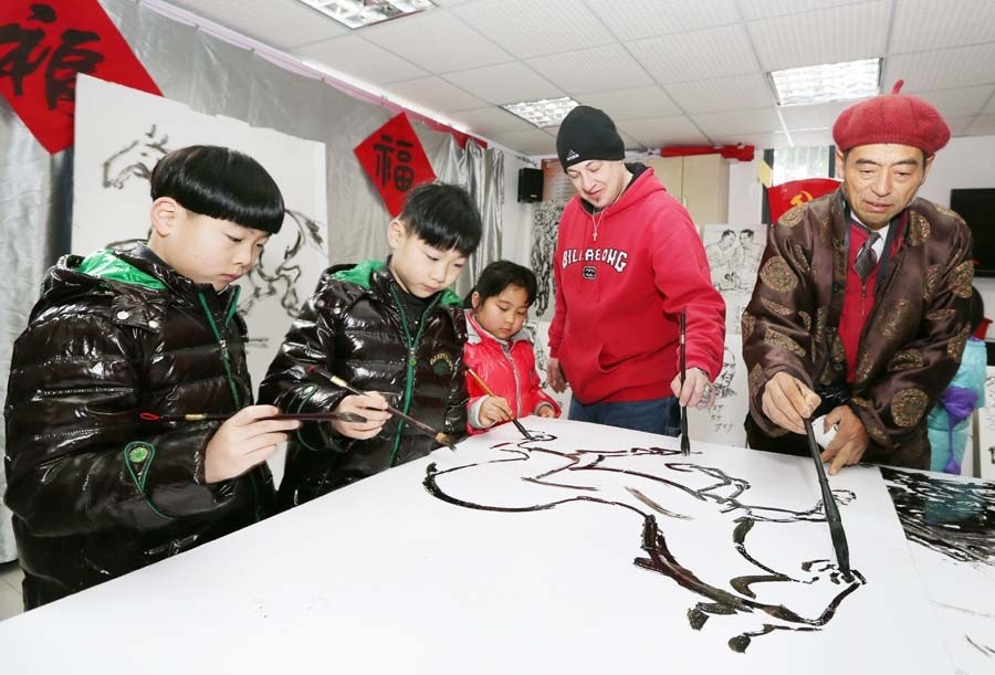 Jonathan, un Américain, a rencontré des artistes folkloristes et des enfants de la communauté de Haocheng pour exécuter une peinture sur le thème du cheval et certains travaux de calligraphie pour accueillir le prochain Nouvel An lunaire -l'Année du Cheval- à Nantong, dans la Province du Jiangsu, le 24 janvier. [Photo Xu Peiqin / Asianewsphoto]