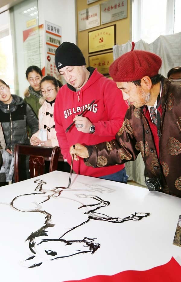 Jonathan, un Américain, a rencontré des artistes folkloristes et des enfants de la communauté de Haocheng pour exécuter une peinture sur le thème du cheval et certains travaux de calligraphie pour accueillir le prochain Nouvel An lunaire -l'Année du Cheval- à Nantong, dans la Province du Jiangsu, le 24 janvier. [Photo Xu Peiqin / Asianewsphoto]