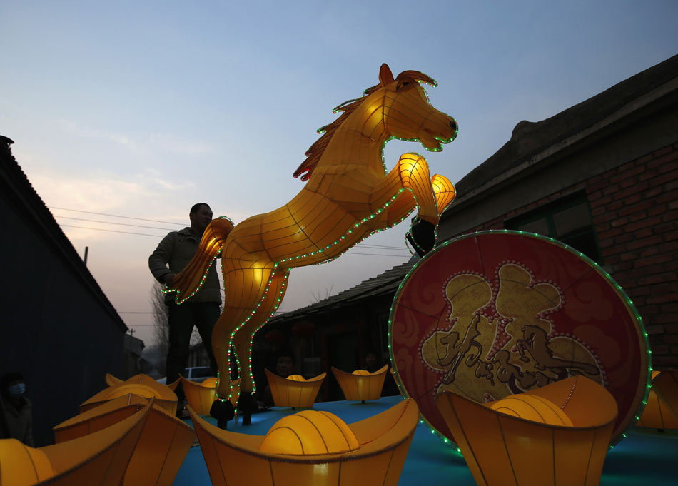 Un employé teste les lumières d'une lanterne en forme de cheval lors d'une séance photo à quelques jours du Nouvel An lunaire chinois, à l'extérieur d'une usine de lanternes à Beijing, le 22 janvier 2014. [Photo / agences]