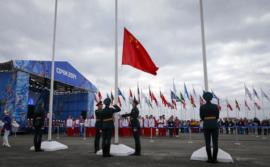 Des soldats russes hissent le drapeau national de la Chine au cours d'une cérémonie de bienvenue organisée pour l'équipe dans le village des athlètes au Parc olympique, avant les Jeux olympiques d'hiver 2014 de Sotchi, le 5 février 2014. [Photo / agences]