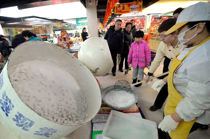 Le 7 février à Handan, un employé d'un supermarché prépare des yuanxiaos, dans la province du Hebei (nord de la Chine), ce qui a attiré les clients curieux. (Photo : Hao Qunying/Asianewsphoto)