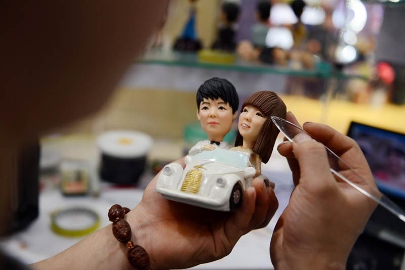 Fu Xinxi, un artiste folklorique de Liaocheng, dans la Province du Shandong, crée un couple de « figurines d'amoureux en pâte », le 9 février 2014. Les figurines en pâte de Fu sont populaires chez les couples pour la Saint Valentin. Elles sont fabriquées à partir de farine de blé, de farine de riz gluant et de glycérine cuites à la vapeur, et sont créées à partir de photos fournies par les couples. [photo Xinhua]