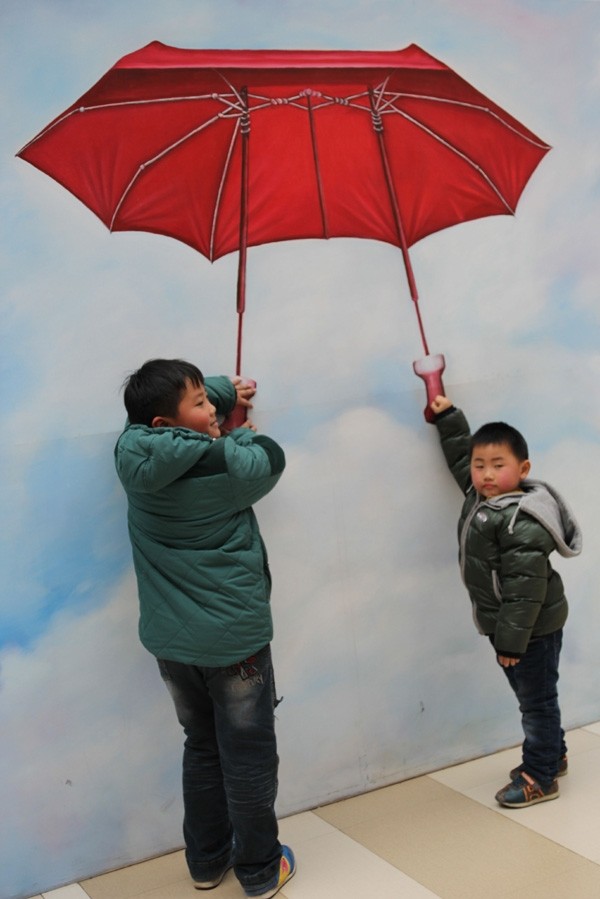 Deux enfants posent pour une photo devant une peinture 3D dans un centre commercial de Qingdao, dans la Province du Shandong, dans l'Est de la Chine, le 11 février 2014. [Photo Huang Jiexian / asianewsphoto]