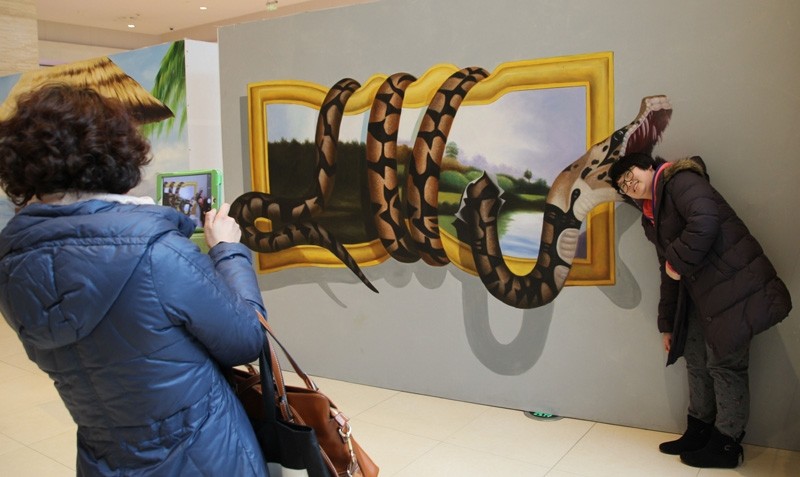Une visiteuse pose pour une photo devant une peinture 3D dans un centre commercial de Qingdao, dans la Province du Shandong, dans l'Est de la Chine, le 11 février 2014. [Photo Huang Jiexian / asianewsphoto]