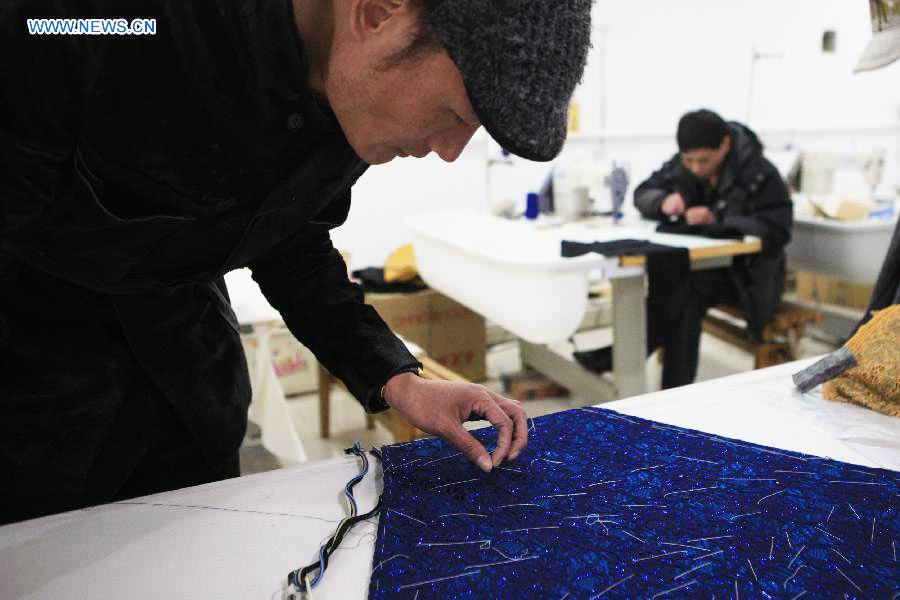 Le designer Laurence Xu (à gauche) examine une de ses créations dans son studio à Beijing, capitale de la Chine, le 17 février 2014. Xu, designer né en Chine dans le Shandong et installé à Paris, montrera ses nouvelles créations lors de la Semaine de la mode de Paris en juillet. [Photo / Xinhua]