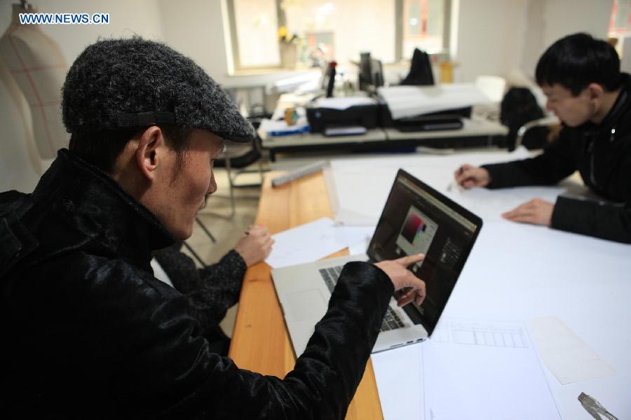 Le designer Laurence Xu (à gauche) parle de ses créations dans son studio à Beijing, capitale de la Chine, le 17 février 2014. Xu, designer né en Chine dans le Shandong et installé à Paris, montrera ses nouvelles créations lors de la Semaine de la mode de Paris en juillet. [Photo / Xinhua]