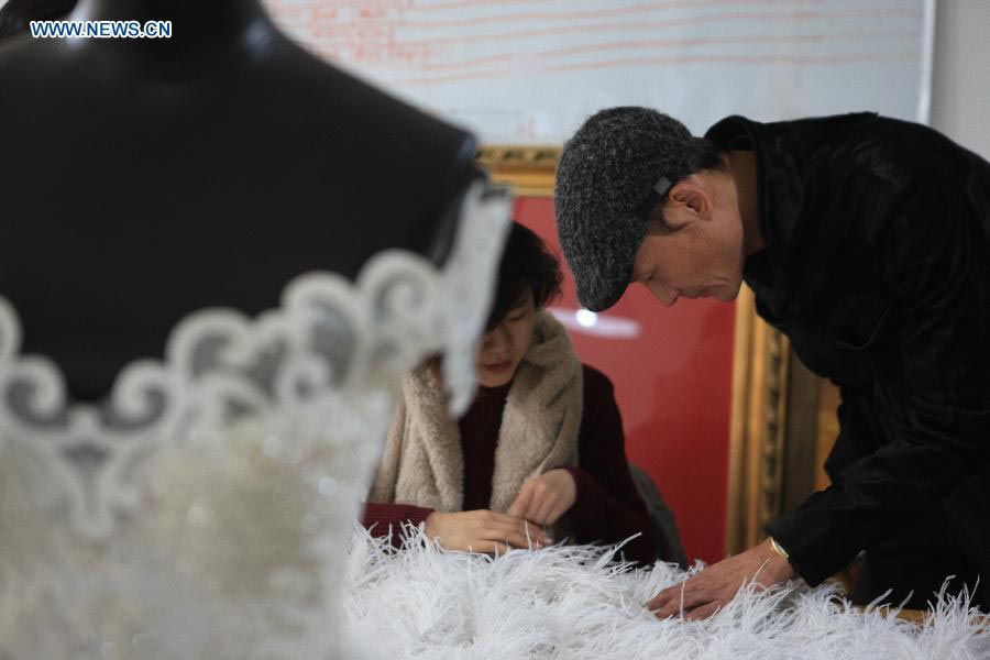 Le designer Laurence Xu dirige la réalisation d'une robe de mariée sur mesure dans son atelier à Beijing, capitale de la Chine, le 17 février 2014. Xu, designer né en Chine dans le Shandong et installé à Paris, montrera ses nouvelles créations lors de la Semaine de la mode de Paris en juillet. [Photo / Xinhua]