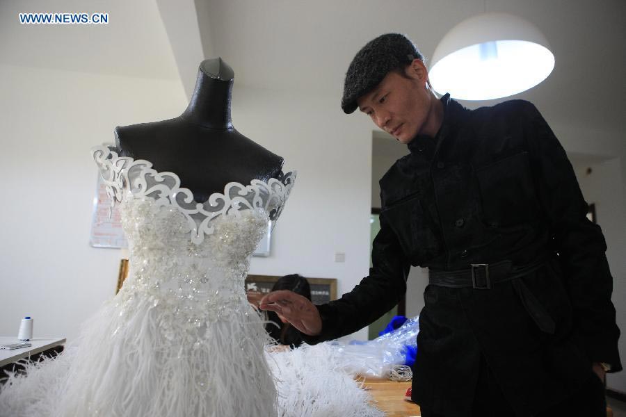 Le designer Laurence Xu vérifie une robe de mariée sur mesure inachevée dans son studio à Beijing, capitale de la Chine, le 17 février 2014. Xu, designer né en Chine dans le Shandong et installé à Paris, montrera ses nouvelles créations lors de la Semaine de la mode de Paris en juillet. [Photo / Xinhua]