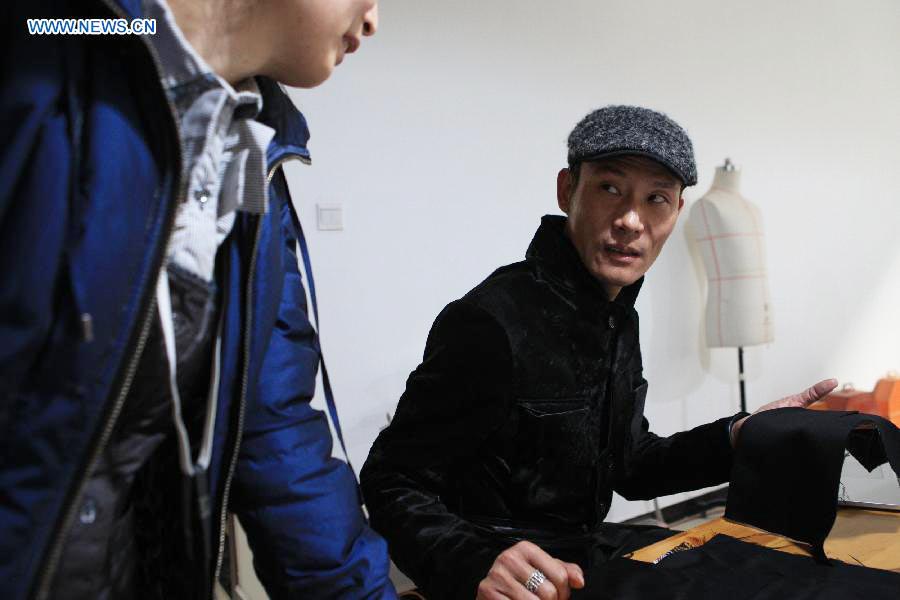Le designer Laurence Xu discute avec une couturière de ses créations à Beijing, capitale de la Chine, le 16 février 2014. Xu, designer né en Chine dans le Shandong et installé à Paris, montrera ses nouvelles créations lors de la Semaine de la mode de Paris en juillet. [Photo / Xinhua]