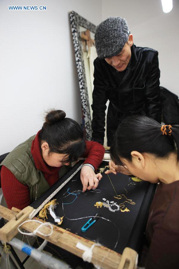 Le designer Laurence Xu (au centre) vérifie la réalisation d'une broderie dans son studio à Beijing, capitale de la Chine, le 17 février 2014. Xu, designer né en Chine dans le Shandong et installé à Paris, montrera ses nouvelles créations lors de la Semaine de la mode de Paris en juillet. [Photo / Xinhua]