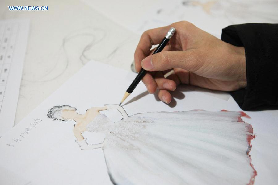 Un peintre fait un dessin pour le créateur Laurence Xu à Beijing, capitale de la Chine, le 17 février 2014. Xu, designer né en Chine dans le Shandong et installé à Paris, montrera ses nouvelles créations lors de la Semaine de la mode de Paris en juillet. [Photo / Xinhua]