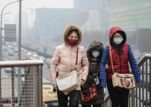 Des jeunes femmes portant un masque facial marchent dans le smog à Beijing, le 20 février 2014. [Photo/Xinhua]